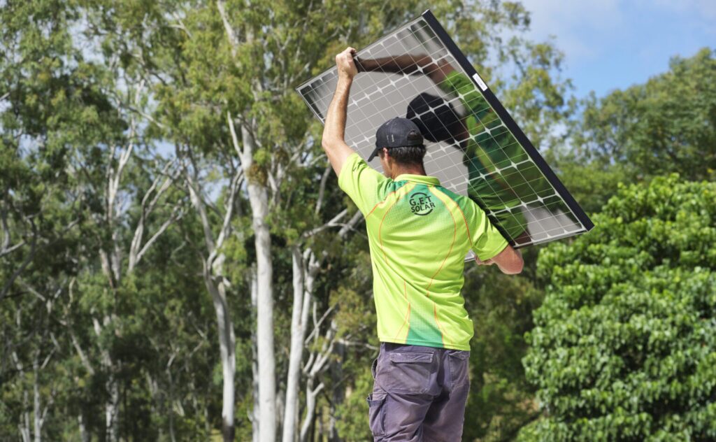 Installer carrying a solar panel to install it on a home