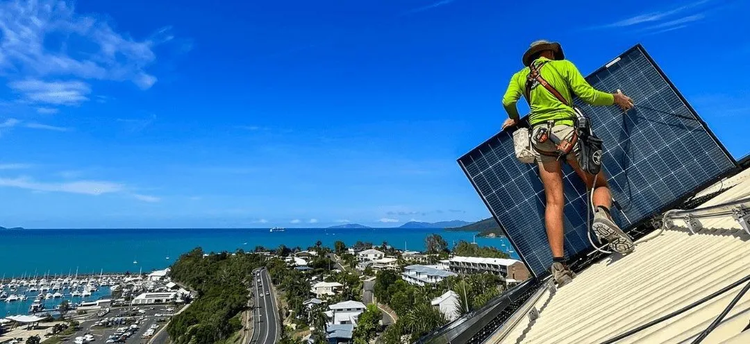 Installer securing a solar panel on a sloped roof in the Whitsundays