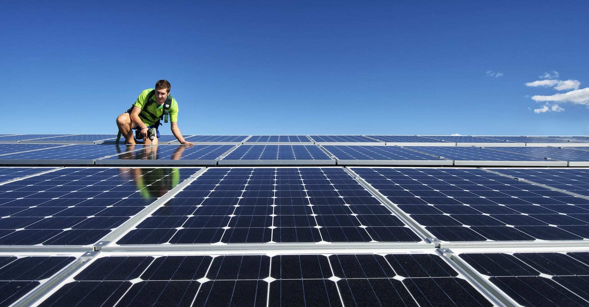 Solar installer on the roof mounting solar panels for renewable energy installation