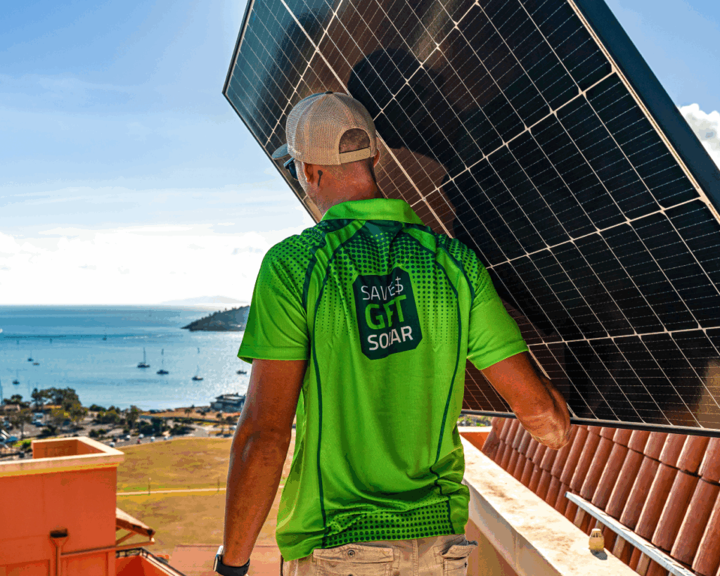 Green energy technologies solar installer carrying a solar panel in whitsundays.