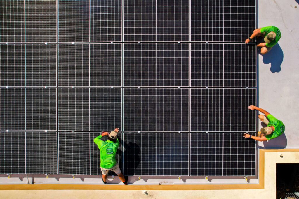 Solar installers, Green Energy Technologies, on roof.